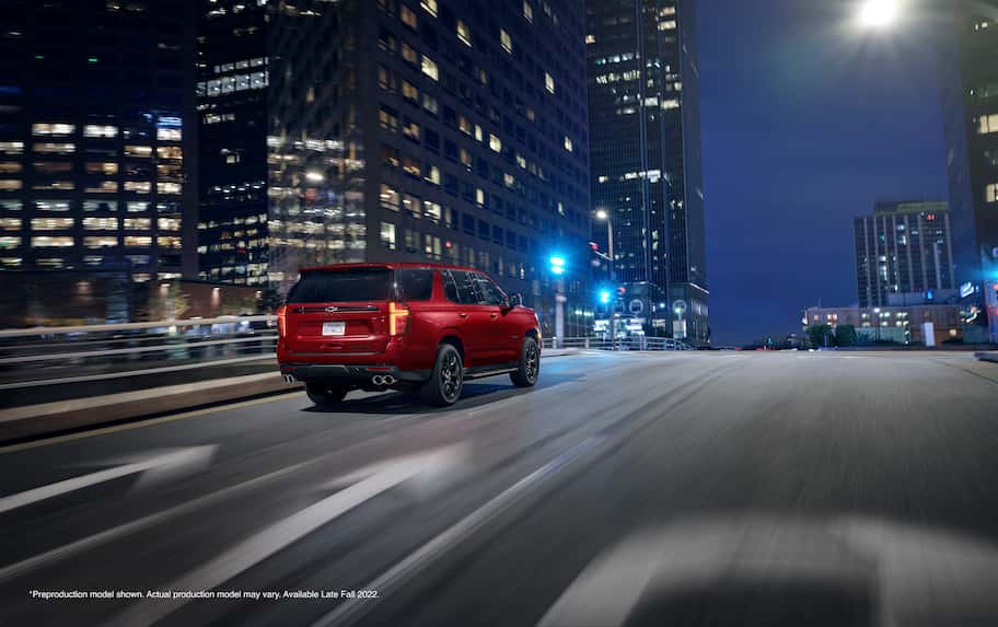 Rear motion shot of the 2023 Chevrolet Tahoe RST Performance Edition with night city backdrop.