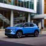 Driver’s side front 3/4 view of 2024 Chevrolet Trailblazer RS in Fountain Blue driving past a building. Preproduction model shown. Actual production model may vary. Available in fall 2023.