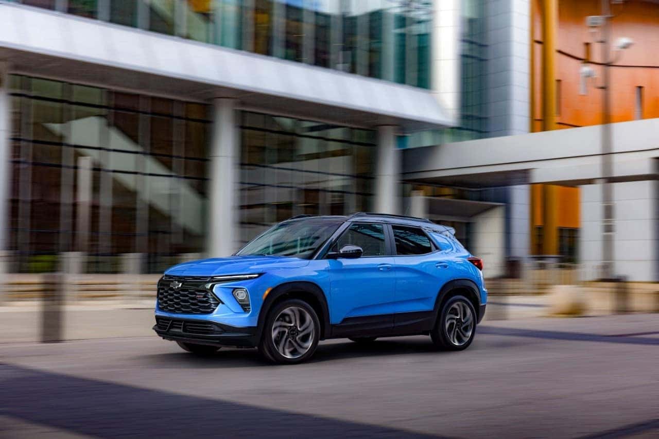 Driver’s side front 3/4 view of 2024 Chevrolet Trailblazer RS in Fountain Blue driving past a building. Preproduction model shown. Actual production model may vary. Available in fall 2023.