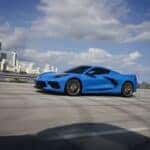 Side profile view of a 2024 Chevrolet Corvette Stingray in Rapid Blue driving over a bridge.