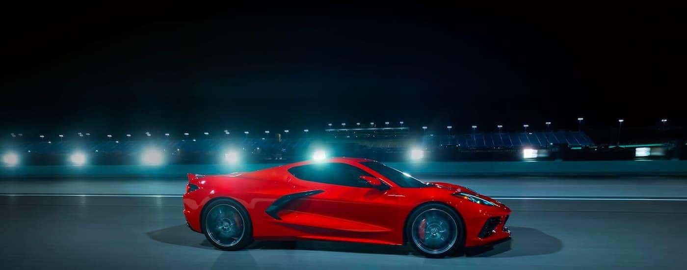 A red 2023 Chevy Corvette is shown from the side on a racetrack at night.