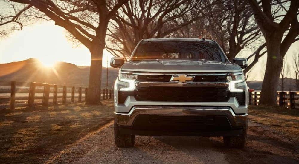 A silver 2023 Chevy Silverado 1500 is shown from the front on a sunny day.