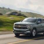 A siver 2024 Chevy Tahoe LT driving on an open country road.
