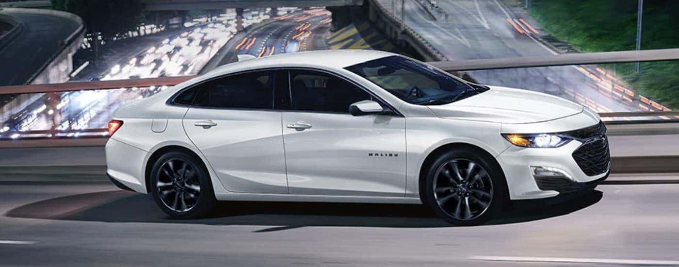 A white 2021 Chevy Malibu is shown driving on an overpass.