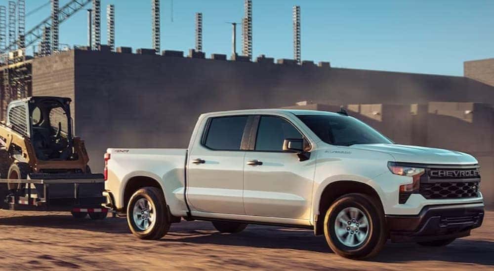 A white 2024 Chevy Silverado 1500 WT is shown towing a trailer after visiting a Chevy dealer near Benton.