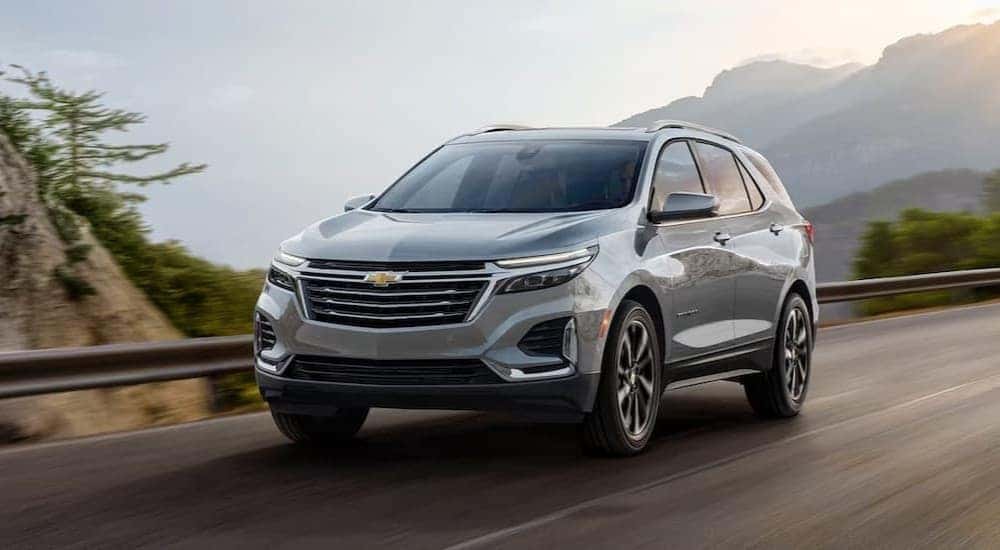 A silver 2024 Chevy Equinox is shown driving near a guardrail.
