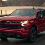 A red 2024 Chevy Silverado 1500 RST Z71 is shown parked near a lake.