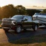 A black 2024 Chevy Silverado 2500 HD High Country towing a boat.