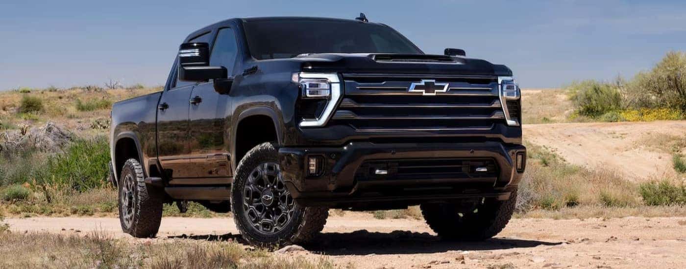 A black 2024 Chevy Silverado 2500HD Midnight Edition is shown parked off-road.