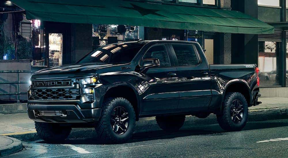 A black 2024 Chevy Silverado 1500 Midnight Trailboss Z71 is shown parked on a city street.