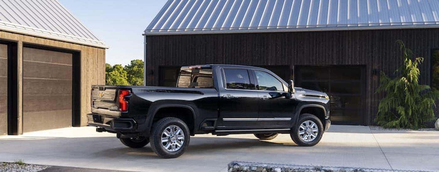 A black 2024 Chevy Silverado 2500 HD High Country is shown from the side after leaving a dealer that has a Chevy Silverado for sale in Shreveport.