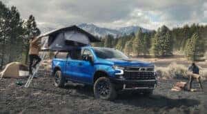 People are shown setting up a campsite near a blue 2023 Chevy Silverado 1500 ZR2.