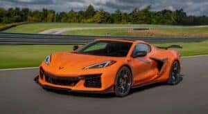 An orange 2024 Chevy Corvette Z06 is shown from the front at an angle.