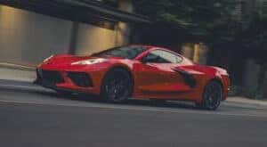 A red 2025 Chevy Corvette Stingray is shown driving to a Chevy dealer near Marshall.