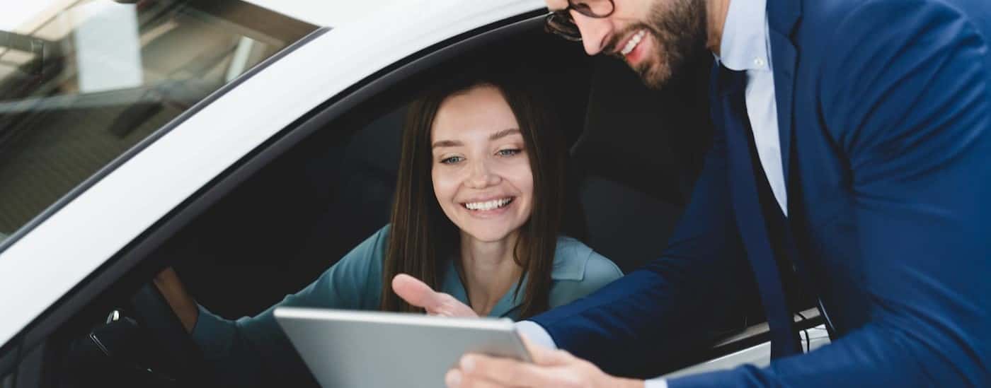 Two people are shown smiling while looking at a tablet.