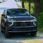 A black 2025 Chevy Tahoe for sale near Marshall driving through a forest road.