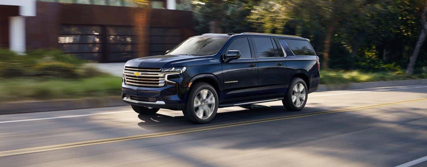 A black 2021 Chevy Suburban High Country is shown driving after visiting a Chevy dealer near Blanchard .