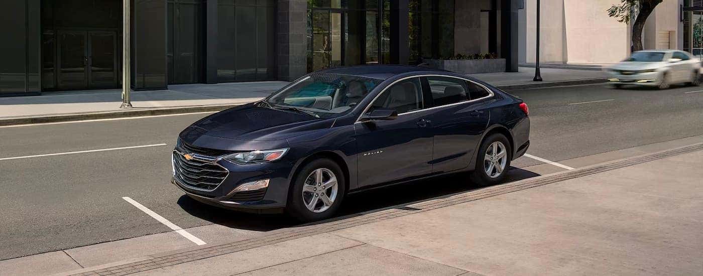A blue 2023 Chevy Malibu for sale is shown parked on a parking spot.
