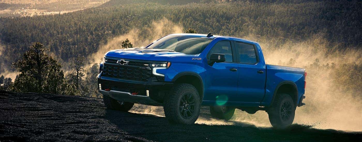 Blue 2025 Chevy Silverado 1500 ZR2 driving off-road after visiting a Chevy dealer near Monroe.