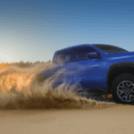 Blue 2026 Chevy Colorado driving on a sand dune