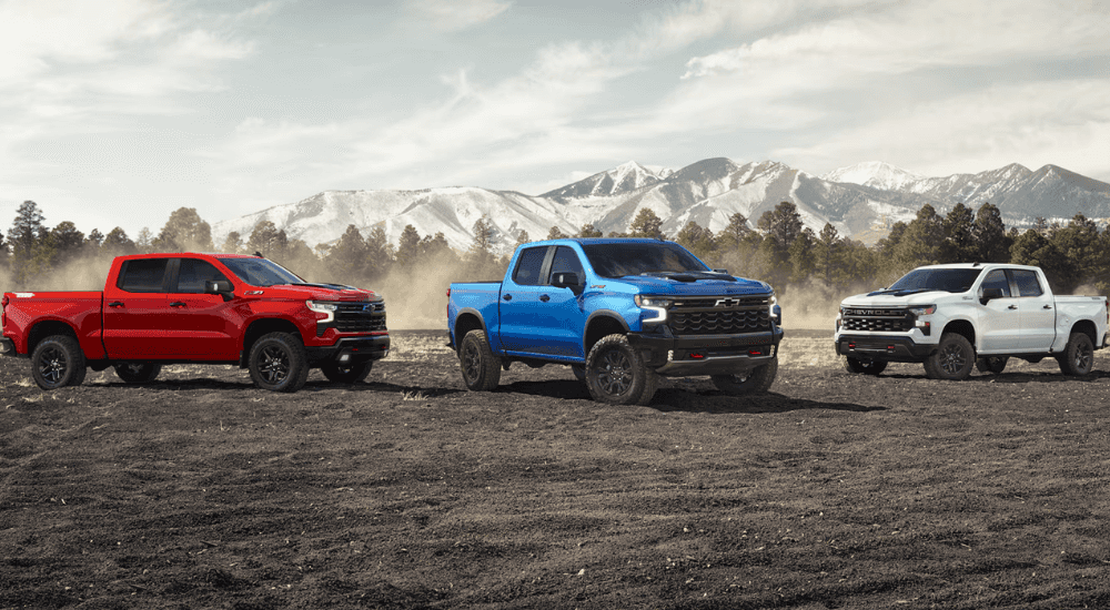 A red, a blue, and a white 2026 Chevy Silverado 1500 parked side by side