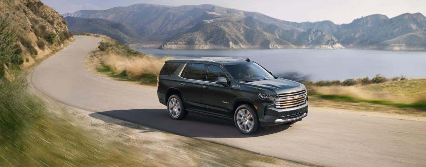Black 2022 Chevy Tahoe High Country driving down a winding road.