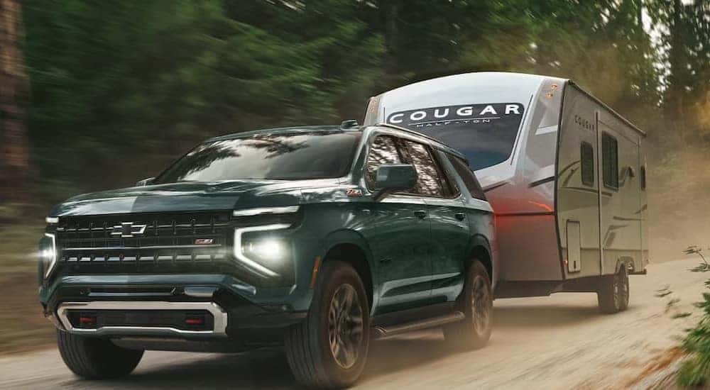 A green 2026 Chevy Tahoe Z71 towing a trailer.