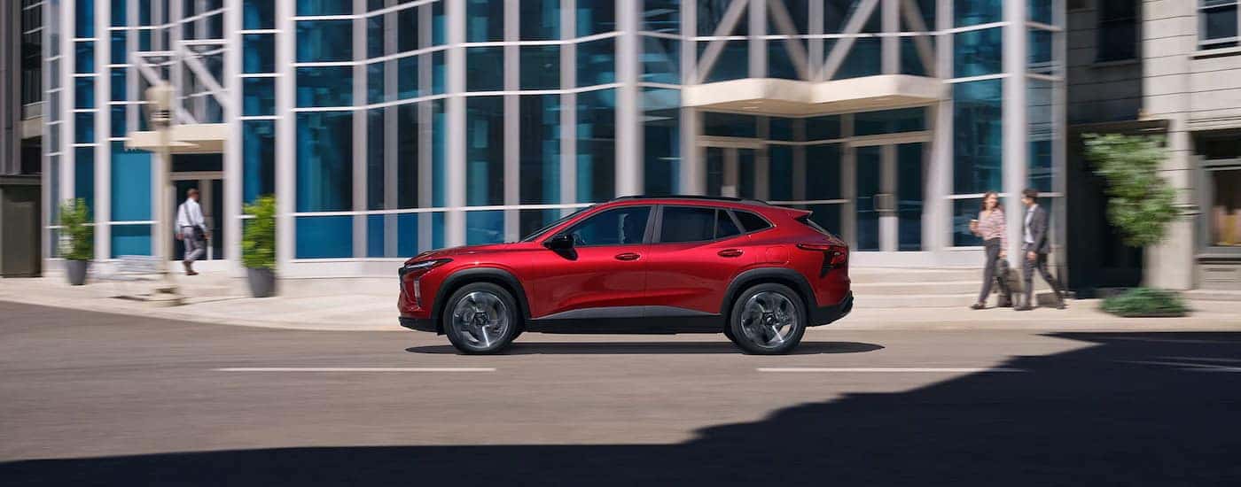 Side of a red 2025 Chevy Trax parked by a curb.