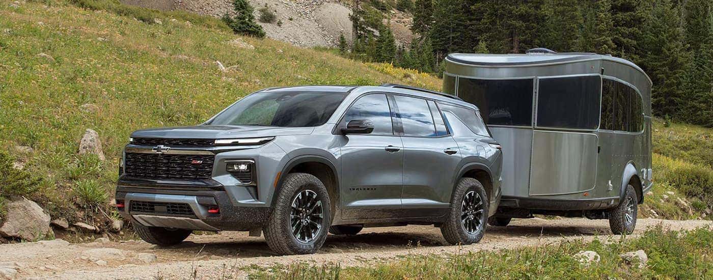 Grey 2026 Chevy Traverse towing a camper van off-road.