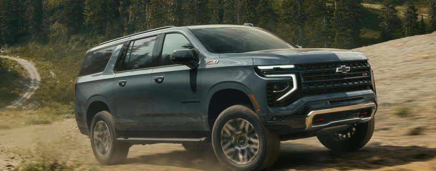 A blue 2026 Chevy Suburban Z71 off-roading on a trail