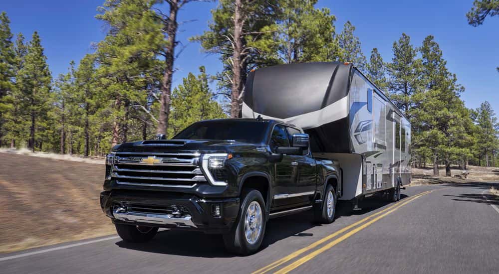 Black 2026 Chevy Silverado 2500 HD towing a camper down the street
