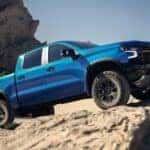 Blue 2026 Chevy Silverado 1500 driving up rocks