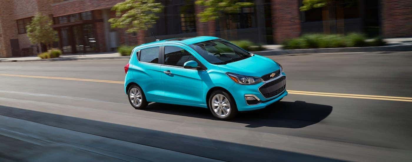 A teal 2021 Chevy Spark is shown driving.