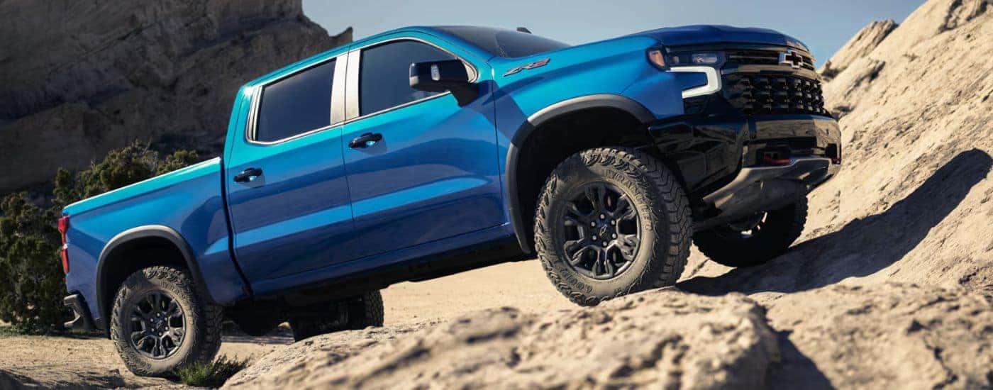 Blue 2026 Chevy Silverado 1500 driving up rocks.