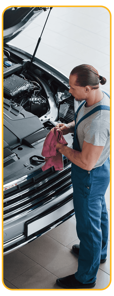 Things to Check When Buying a Used Car | CMA Chevrolet of Martinsburg in Martinsburg, WV | Mechanic whipping his hands with a clean rag while standing beside car with hood open