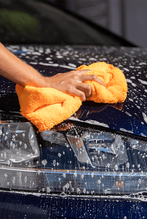 Accessories that help keep your Chevrolet protected at CMA Chevrolet of Martinsburg in Martinsburg, WV | Person using orange color sponge to clean the exterior of their car  