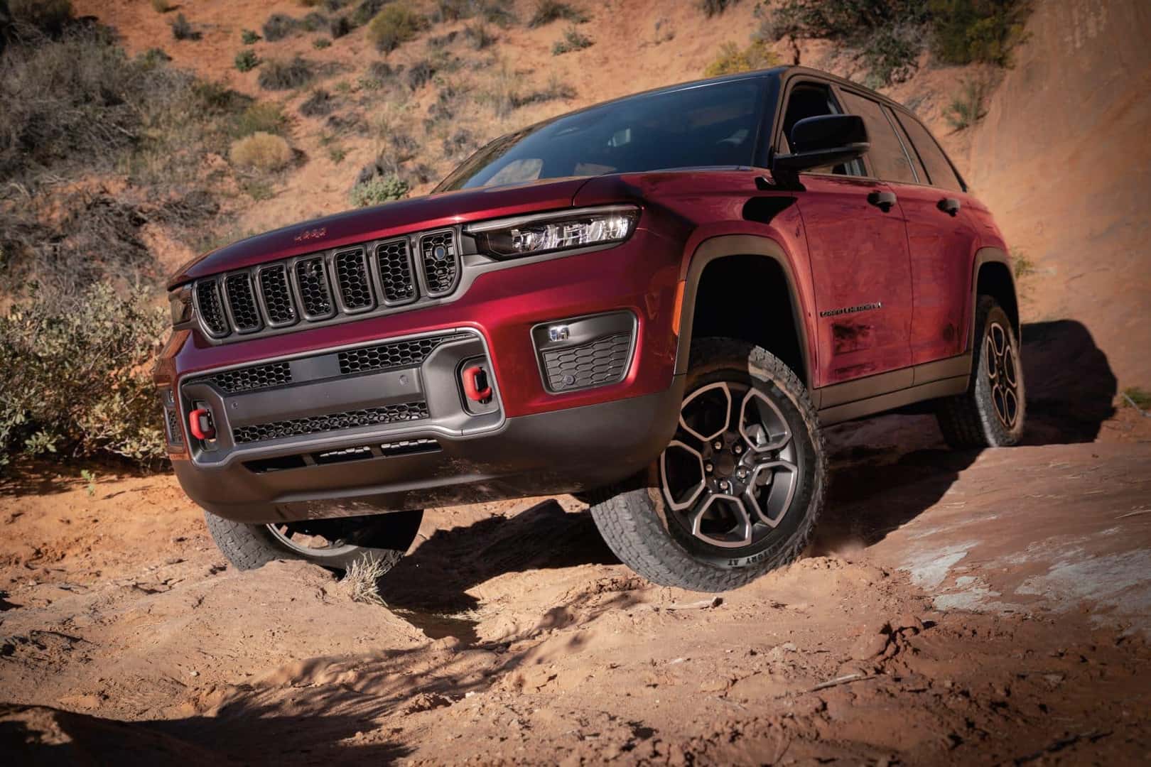 Red Jeep Grand Cherokee clambering over rocky surface
