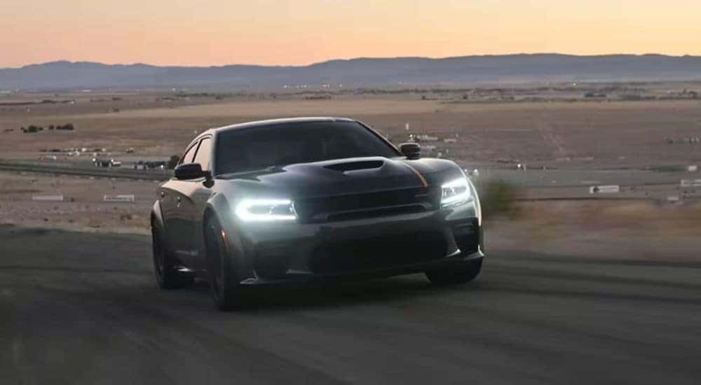 A gray 2023 Dodge Charger Scat Pack Widebody is shown driving on a track.