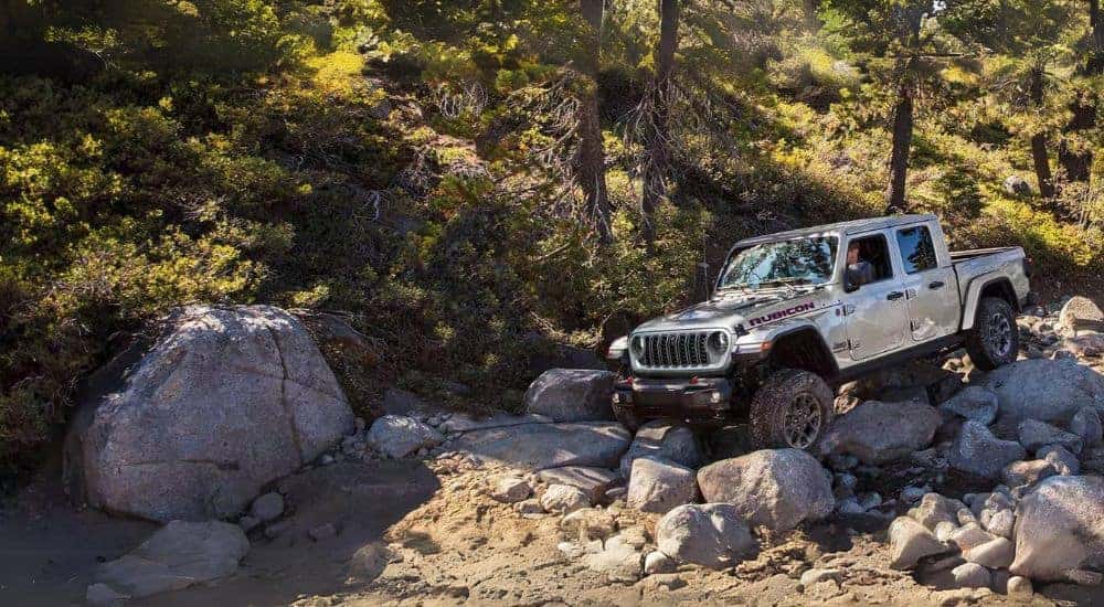 A white 2024 Jeep Gladiator Rubicon off-roading over rocky terrain.