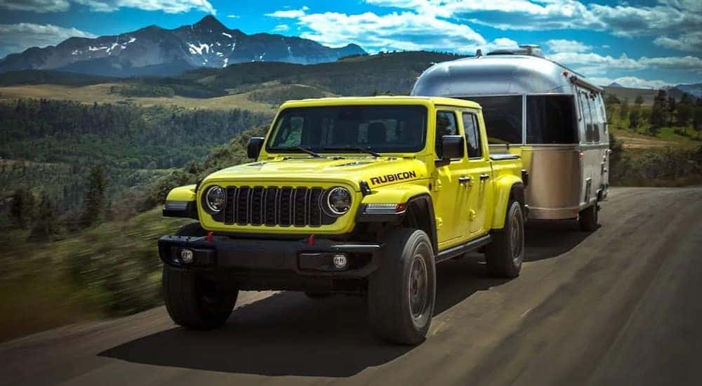 A yellow 2024 Jeep Gladiator Rubicon is shown towing a trailer.