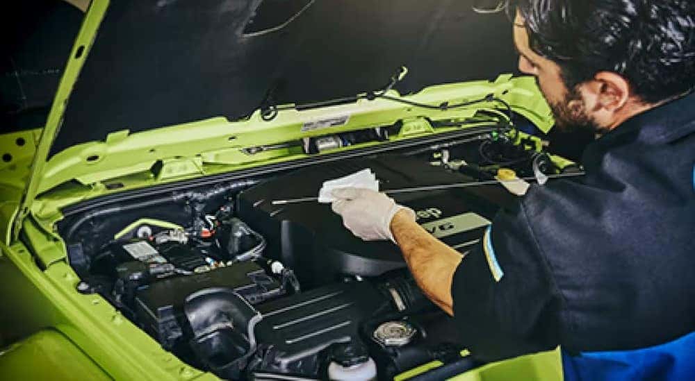 A technician is shown checking a dipstick in a Jeep.