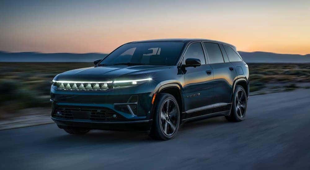 A blue 2024 Jeep Wagoneer S driving on a dirt road.
