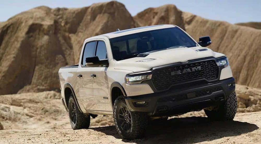 A white 2025 Ram 1500 Rebel driving off-road in a desert.