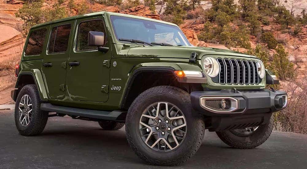 A green 2025 Jeep Wrangler Sahara is shown from the front at an angle after leaving a Jeep dealer near Shelby.