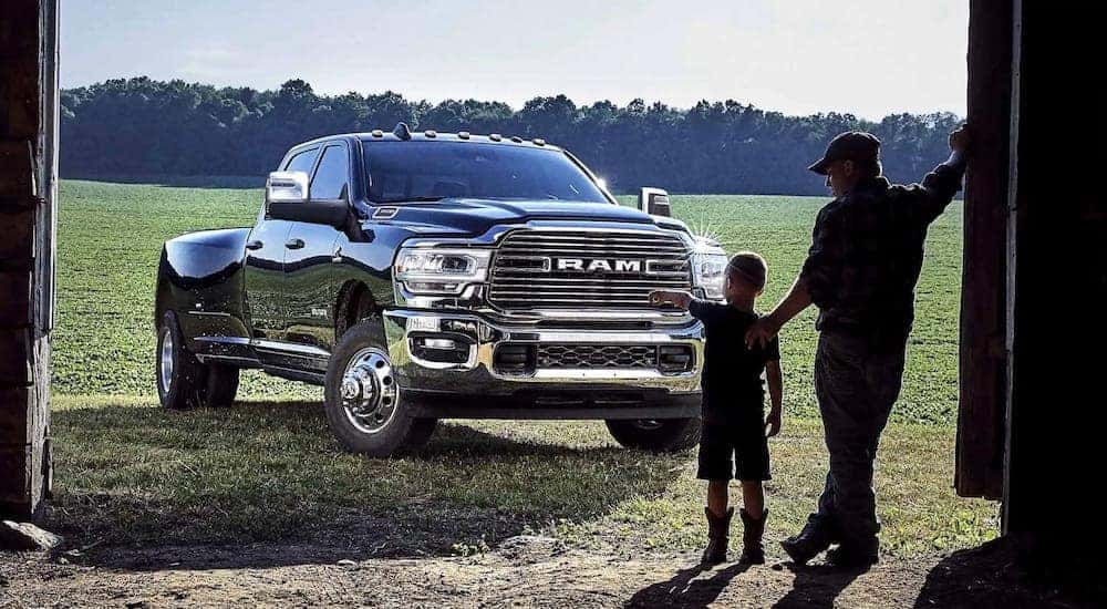 Two people standing in front of a black 2024 Ram 3500 parked by a barn.