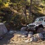 A white 2024 Jeep Gladiator Rubicon driving over a pile of boulders.