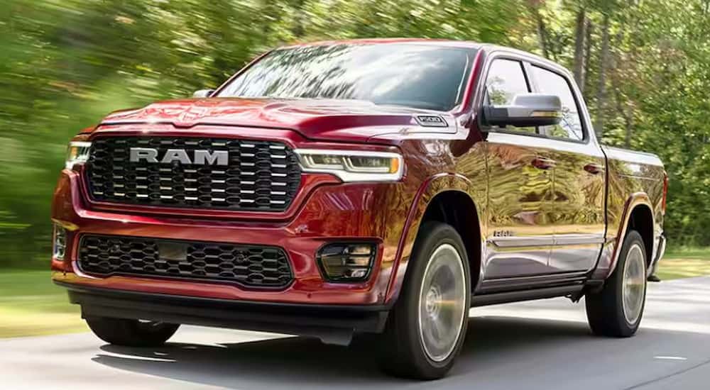 A red 2025 Ram 1500 for sale is shown driving on a backroad.