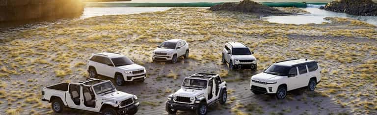 Jeep SUV and Wrangler lineup in a coastal outdoor setting