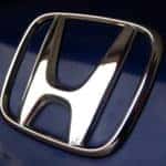 Close-up of silver honda emblem on black honda car