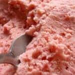 A silver spoon sitting in fresh strawberry ice cream
